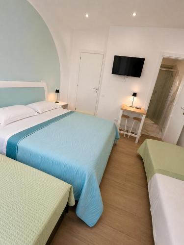 a bedroom with two beds and a tv on the wall at Riviera AlbaChiara B&b in Anzio