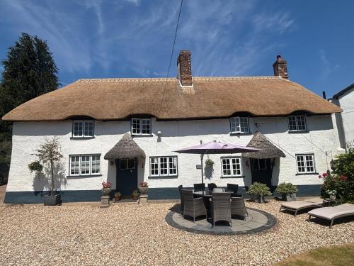 a large white house with a table and chairs at Cotford Cottage in Sidmouth
