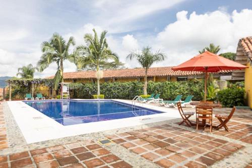 a pool with a table and chairs and an umbrella at Decameron Panaca - All Inclusive in Quimbaya