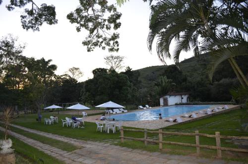 una piscina con sedie e persone sedute intorno ad essa di Fazenda Hotel Jatahy a Cavaru