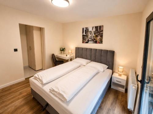 a bedroom with a large bed with white sheets at Apartmani Sjenjak Prestige in Tuzla