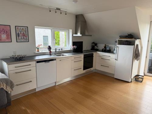 a kitchen with white cabinets and a white refrigerator at Kystvejen Øster Hurup in Hadsund