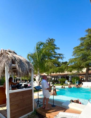 Ein Mann steht neben einem Pool in einem Ferienresort. in der Unterkunft La Siègià Resort spa in Massa Marittima