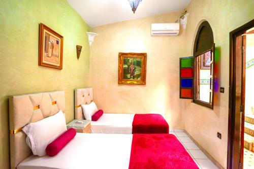 a bedroom with two beds with red pillows at Riad Nezha avec piscines jacuzzi parking à quelques minutes à pied du centre-ville in Marrakesh