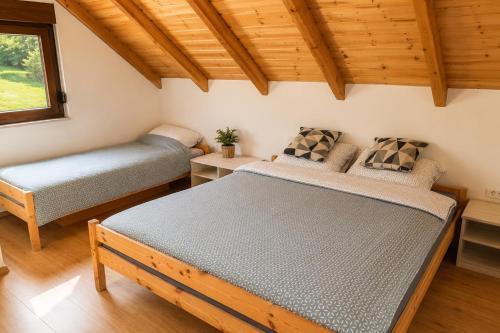 two beds in a room with wooden ceilings at Srce Baranje in Podolje
