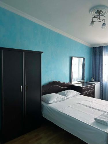 a bedroom with a bed and a blue wall at Hotel Lika in Batumi