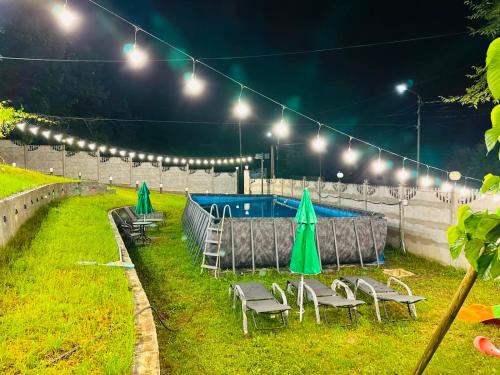 a yard with chairs and umbrellas and lights at night at Serenity Likani Villa Hotel in Borjomi