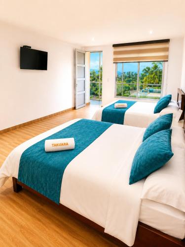 two beds in a hotel room with a television at Hotel Takuara in Vergara