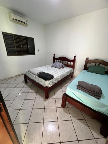 two beds sitting in a room with a window at Casa ampla central in Dourados