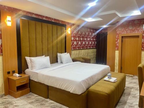 a bedroom with a large bed and a stool at Goldstep Hotel Effurun in Warri