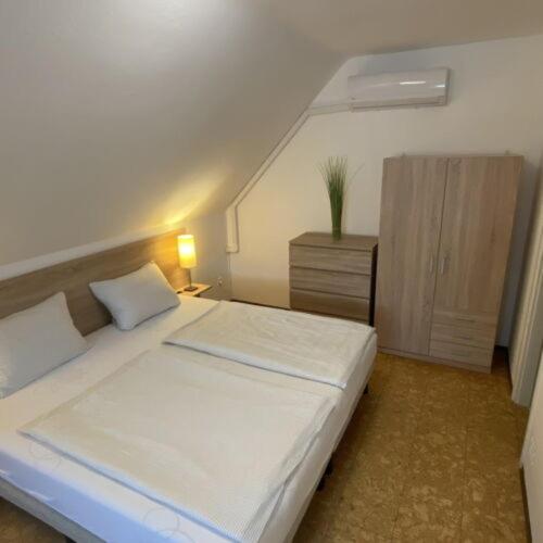a bedroom with a white bed and a dresser with a night stand at Greenhouse Apartman in Zalakaros