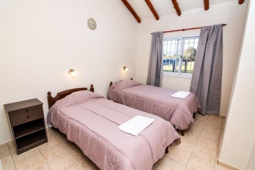 two beds in a room with a window at Entre Hileras - Las Rabonas in Las Rabonas