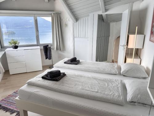 a white bedroom with two beds and a large window at Al Paradiso by Fewotessin in Ronco sopra Ascona