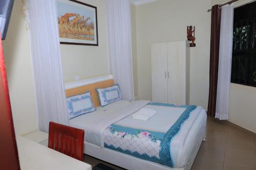 a small bedroom with a bed and a table at Bavah Airport Hotel in Entebbe