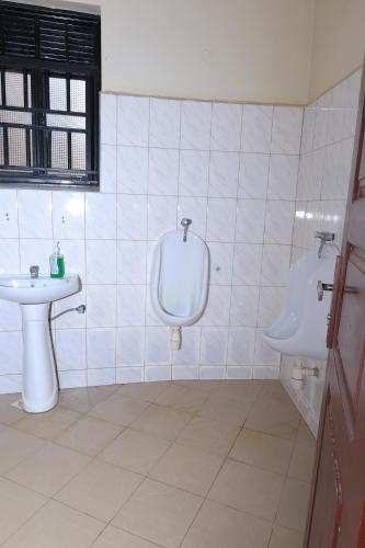 a white bathroom with a sink and a urinal at Bavah Airport Hotel in Entebbe