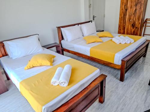 two beds with yellow and white pillows in a room at Shalom Resorts Yala in Tissamaharama