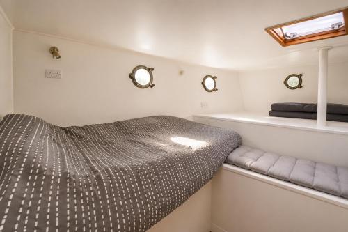 a bed in a small room with two mirrors at Historic Dutch Barge, Idyllic location in London