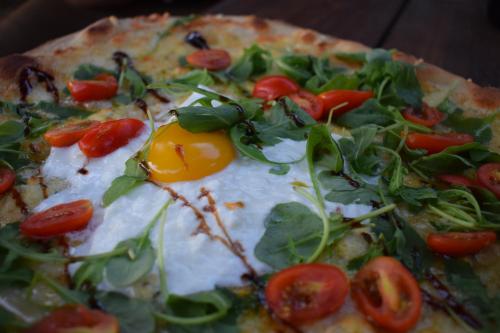 a pizza with tomatoes and an egg on it at N5 Emplacement tente van camping-car in Saint-Aubin-de-Nabirat