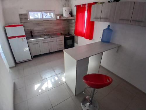 a kitchen with a counter and a red stool in it at Hospedaje Cosquin in Cosquín