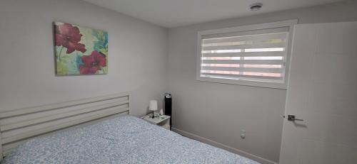 a white bedroom with a bed and a window at La Rose des Prairies -The Prairie Rose in Calgary