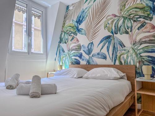 a bedroom with a large white bed with a tropical wallpaper at Le Grand Sault - Hyper-Centre in Grenoble