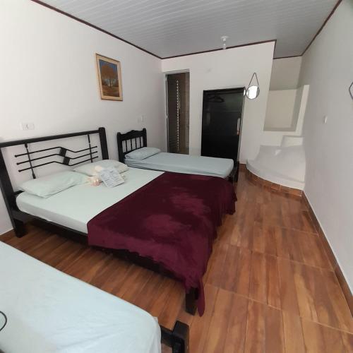 two beds in a room with wooden floors at Pousada Sossego da Vila - Trindade Paraty in Trindade