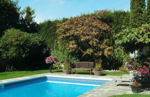 a swimming pool with a bench and some flowers at The Stone Hedge Bed and Breakfast in Richmond