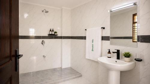 a white bathroom with a sink and a shower at Greenfield Villa D- Diani in Diani Beach