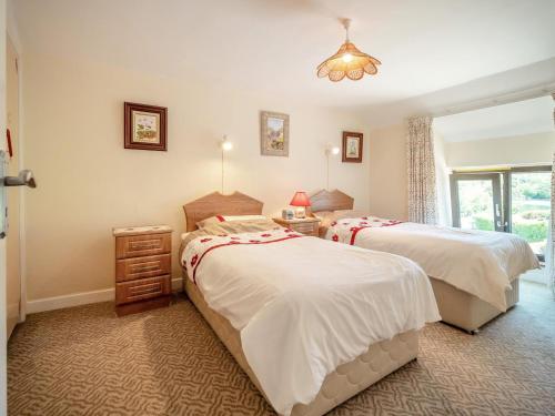 a bedroom with two beds and a table and a window at 3 Bed in Glengarrff oc-i089 in Glengarriff
