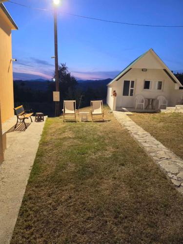 a group of chairs sitting in the grass near a house at Jezerina in Šavnik
