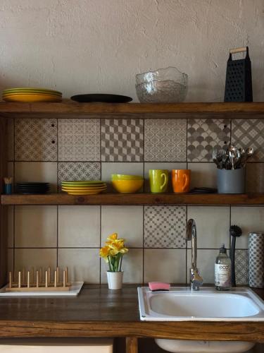 a kitchen with a sink and a shelf with dishes at Central & Quiet Cēsis Stay in Cēsis