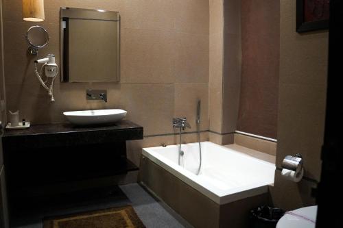 a bathroom with a tub and a sink at Silver Palm Hotel & Resorts in Malaut