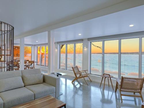 a living room with a couch and chairs and the ocean at VILLA-29 Spa, Sauna, Sunset & Waterfront View in Sainte-Petronille