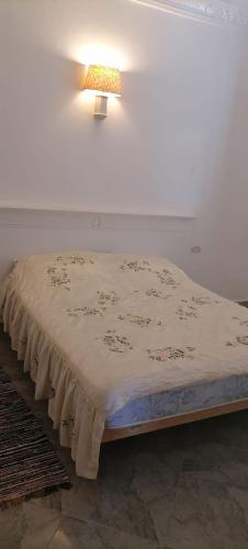 a bed in a room with a lamp on the wall at Maison Souad Guest House in Chott Meriem
