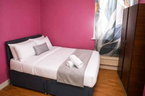 a bed in a room with a pink wall at Property Reality in London