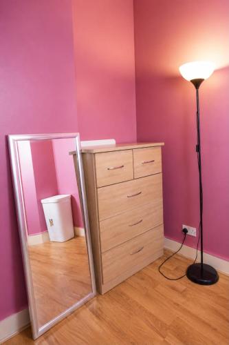 a bedroom with a dresser and a mirror and a lamp at Property Reality in London