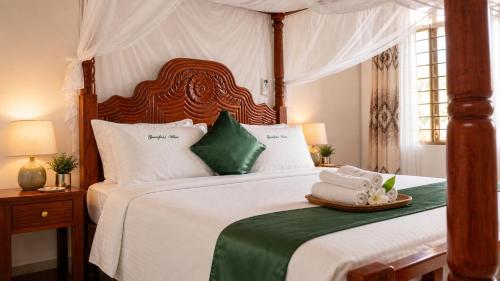 a bedroom with a canopy bed with towels on it at Greenfield Villa D- Diani in Diani Beach