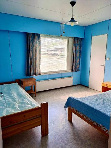 a blue room with two beds and a window at Erillinen talo Kiuru in Nilsiä