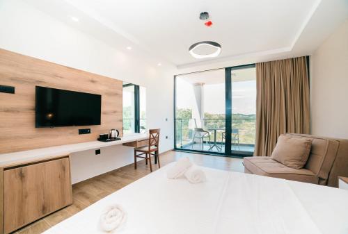 a living room with a television and a desk with a chair at Velmare Inn in Ulcinj