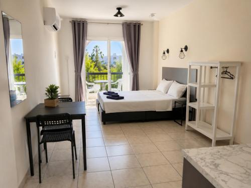 a bedroom with a bed and a desk and a window at Summer's Hotel Apartments in Ayia Napa
