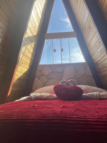 a heart pillow on a bed in front of a window at Pérola Cabana in Serra de São Bento