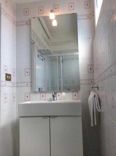 a white bathroom with a sink and a mirror at Hotel Merano in Grado
