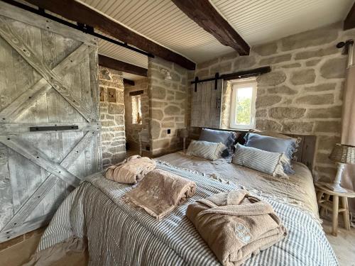 a bedroom with a large bed with a stone wall at Le Petit Refuge - La Petite Longère in Rahon