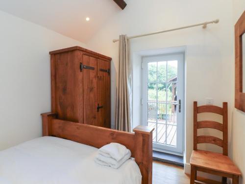 a bedroom with a bed and a wooden cabinet and a window at Beudy'r Wennol in Caernarfon