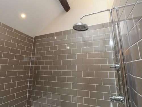a bathroom with a shower with gray tiles at Beudy'r Wennol in Caernarfon