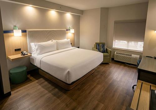 a bedroom with a large white bed and a chair at Garner Hotel Frederick Southeast by IHG in Frederick