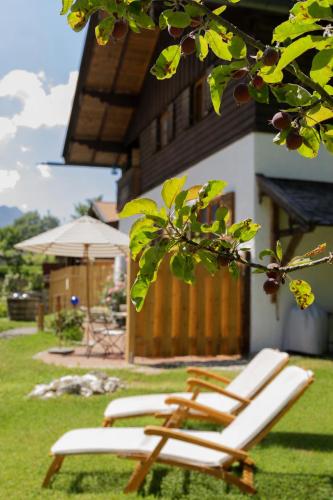 two lounge chairs sitting in the grass in front of a house at Landhaus No 12 mit privater Sauna in Bayrischzell