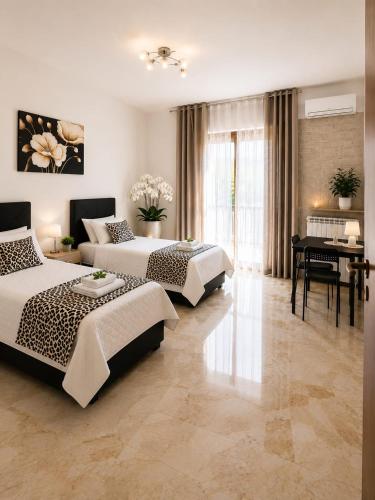 a bedroom with three beds and a table and a desk at Appartamento Orchidea in Monfalcone