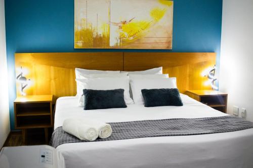 a bedroom with a large white bed with two pillows at Imperial Suzano Shopping Hotel in Suzano
