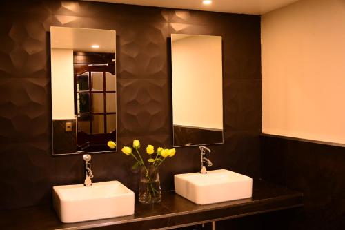 two sinks in a bathroom with two mirrors and flowers at Hotel Imperial in Xalapa
